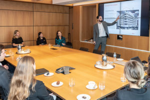 A man gives a presentation to a table of onlookers