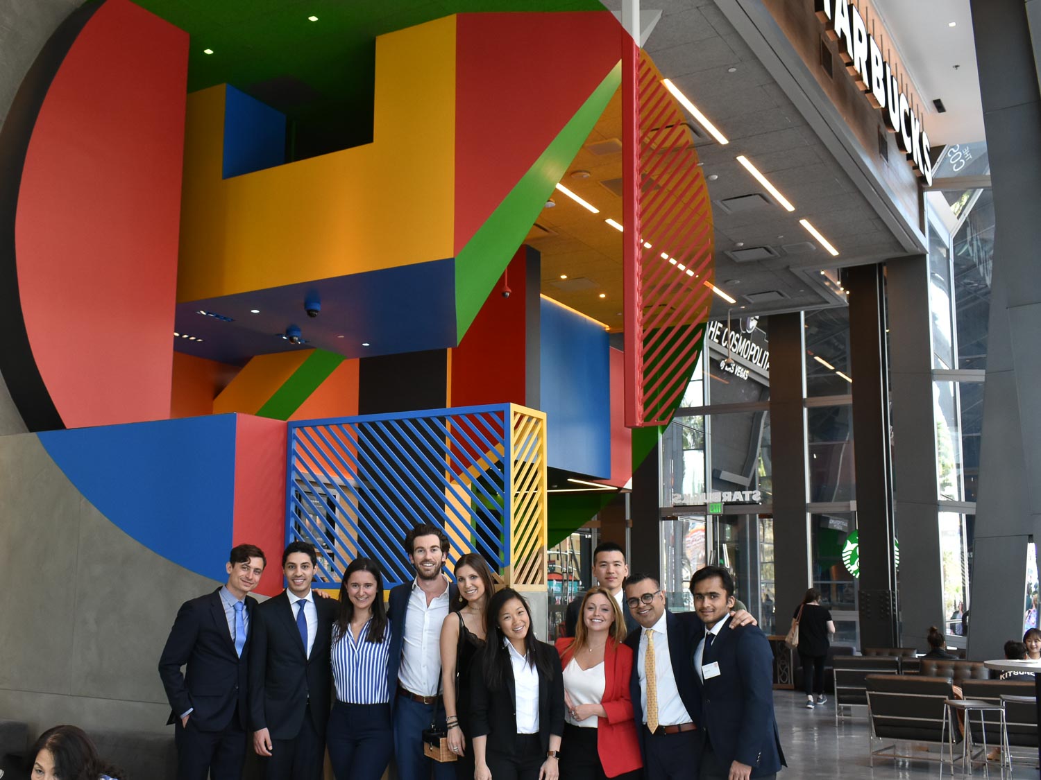 Students stand in front of a brightly colored sign in a hotel lobby