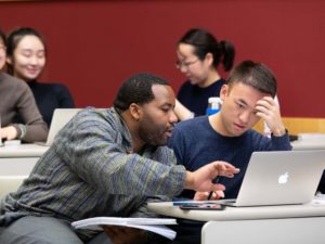 Two students look at a laptop screen together