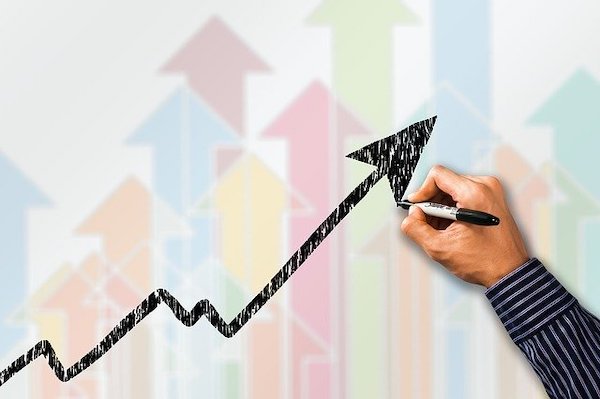 A man draws an upward profit arrow on a whiteboard