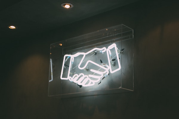 Image of neon sign depicting two hands shaking