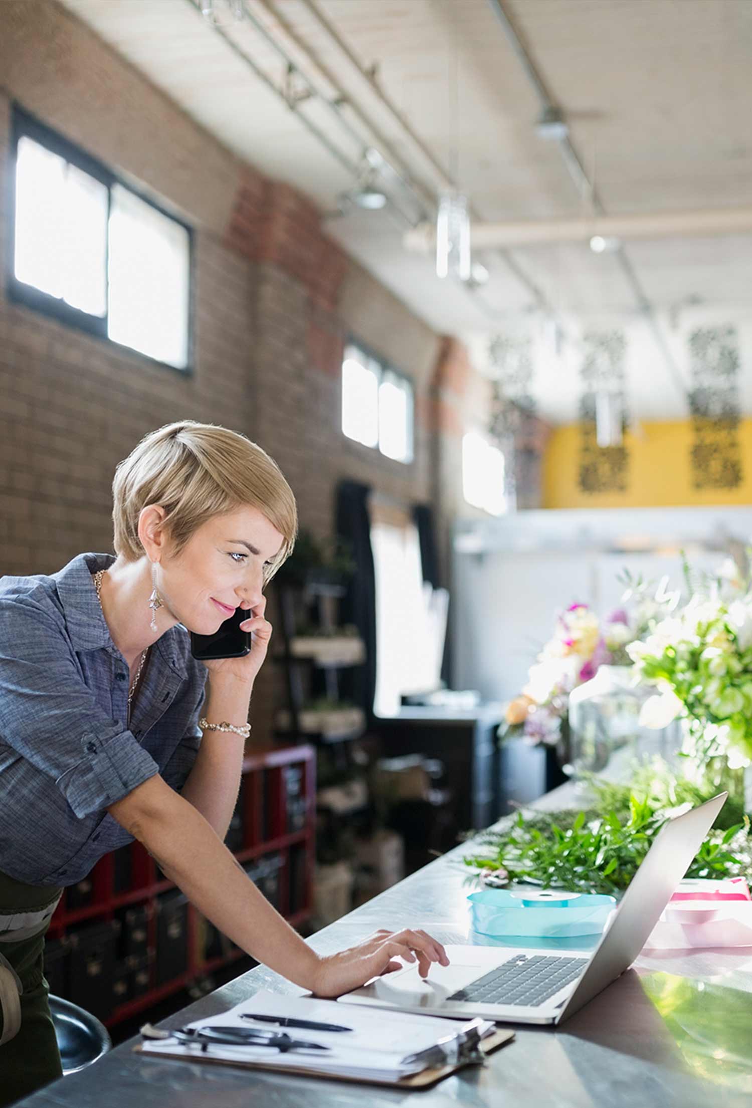 Woman on a cellphone working on a laptop