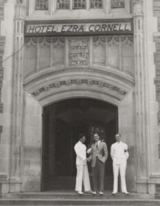 students stand below hotel ezra corell sign on campus building
