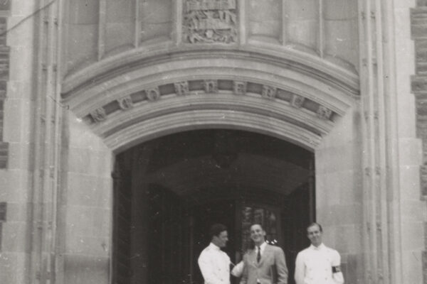 students stand below hotel ezra corell sign on campus building