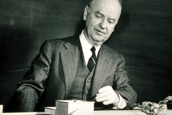 dean meek overlooks a small model of statler hall.