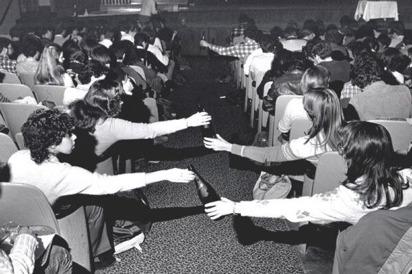students pass bottles of wine across an aisle during a wine course