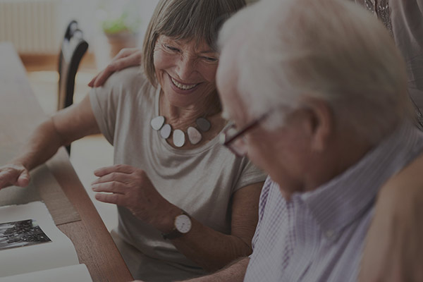 photo of an elderly couple sitting next to each other and looking at a photo album.