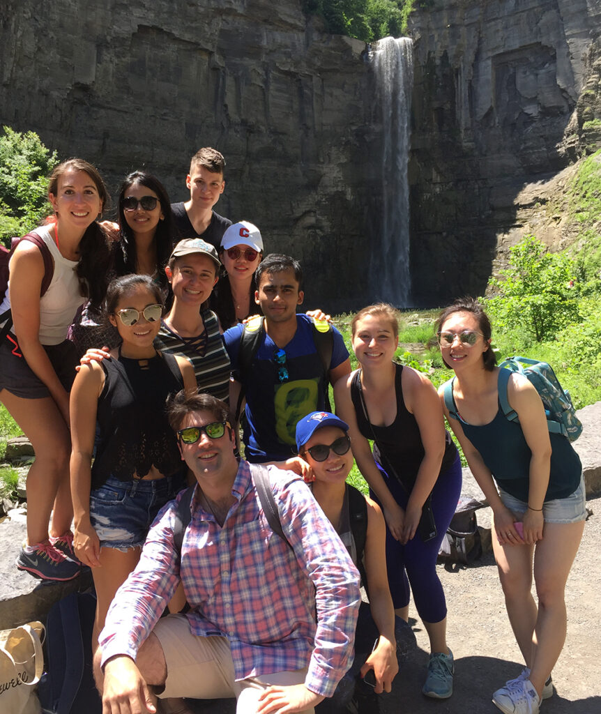 Students pose in front of a waterfall in the Ithaca area.
