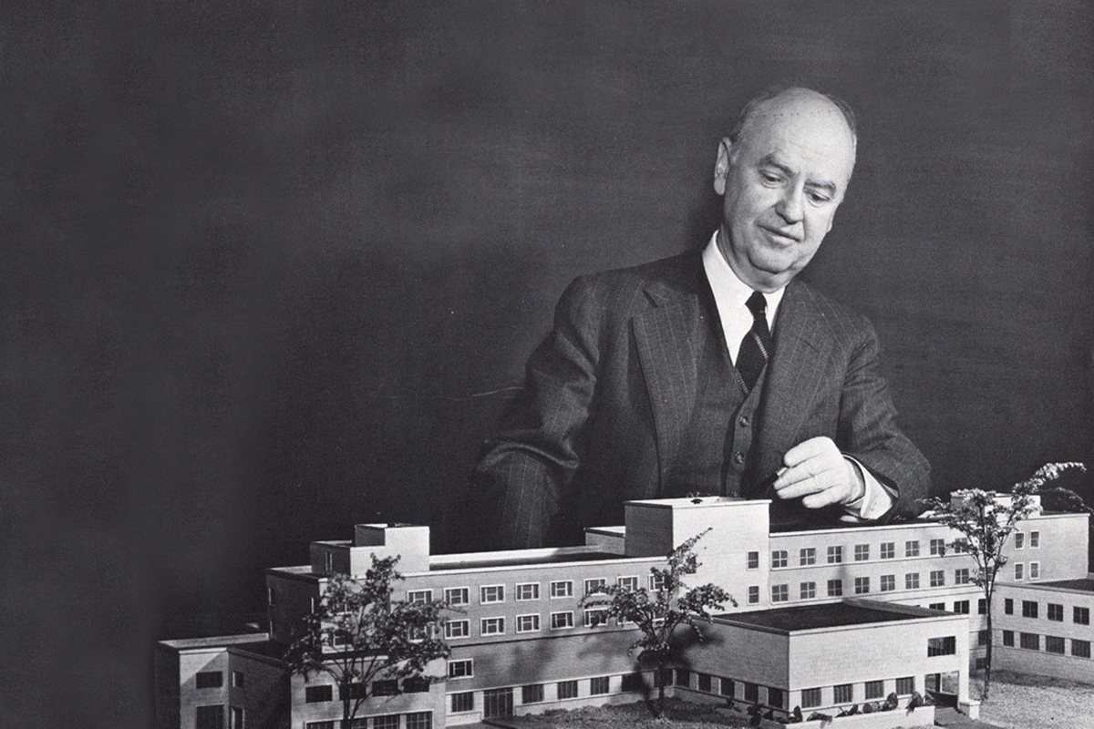 Black and white photo of Howard Bagnall Meek, founding dean of the Nolan Hotel School, surveying a model of Statler Hall during the 1940s.