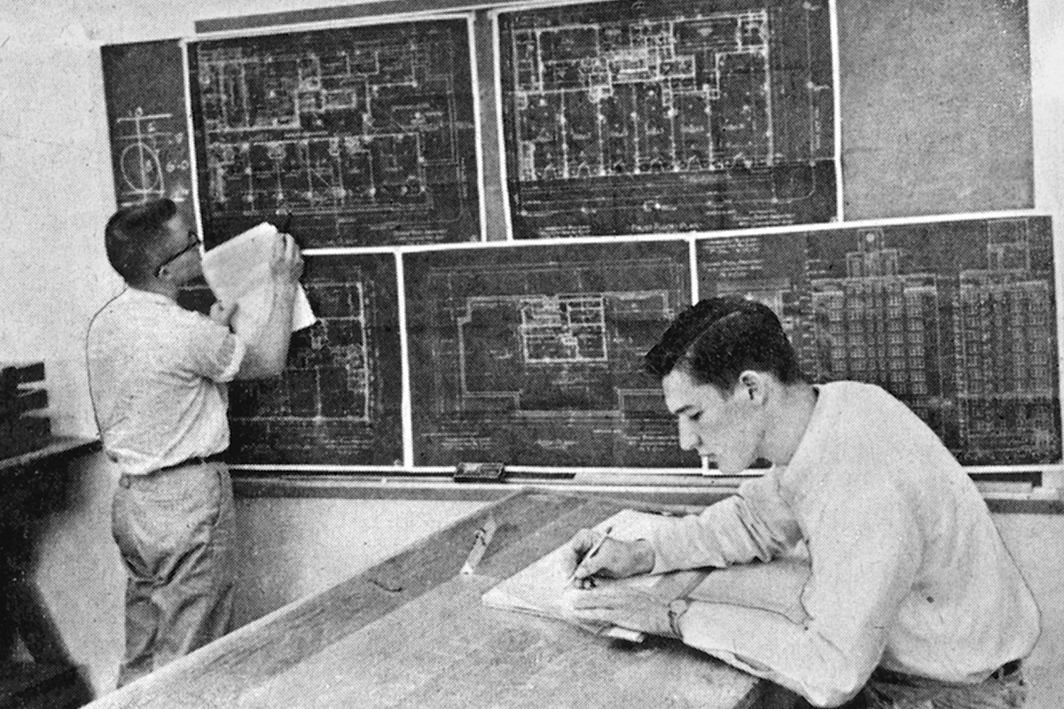 Black and white photo of two men in a drafting room.