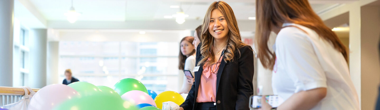 Woman in business attire with multicolored balloons.