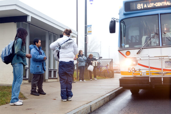 People stand at a bus stop as a bus approaches.