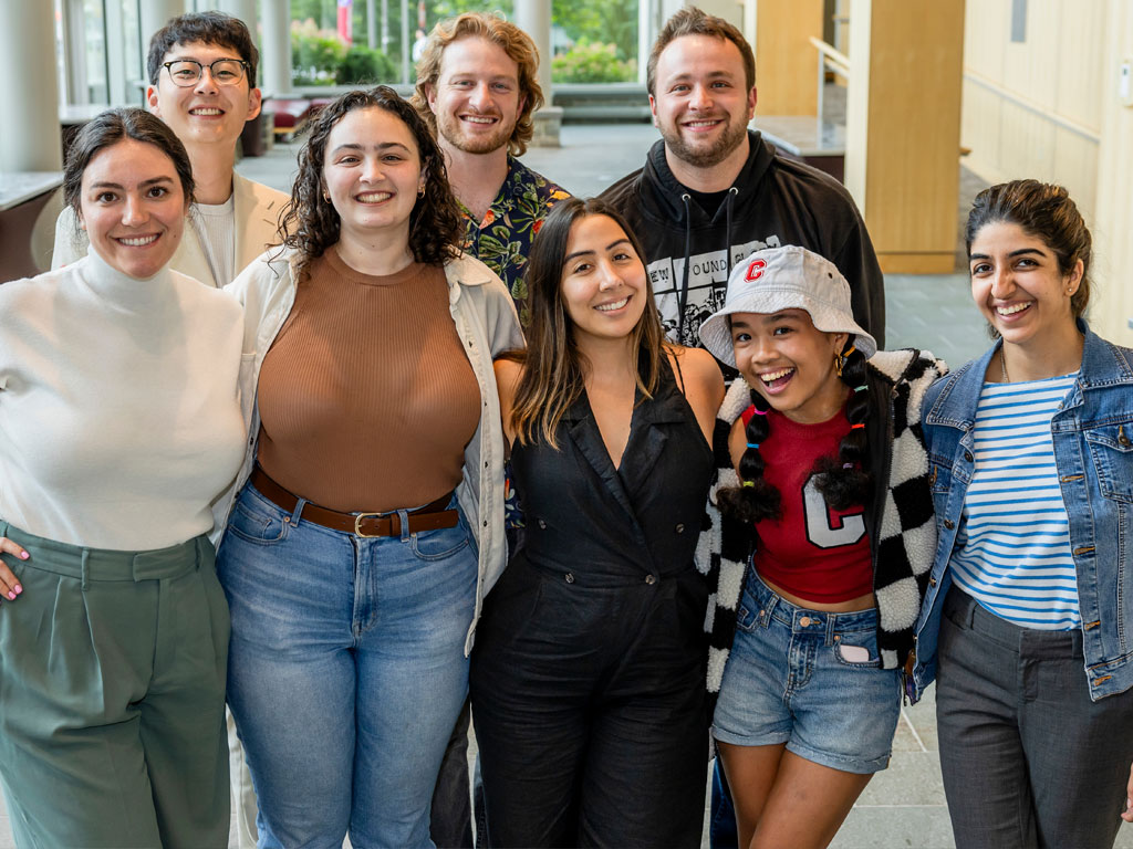 Students stand together with their arms around each other smiling.