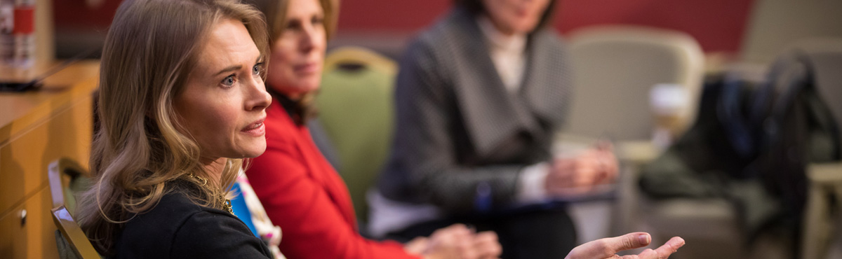 A woman in focus in the foreground with other women out of focus in the background.