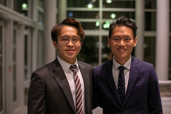 Two men dressed in suits standing side by side.