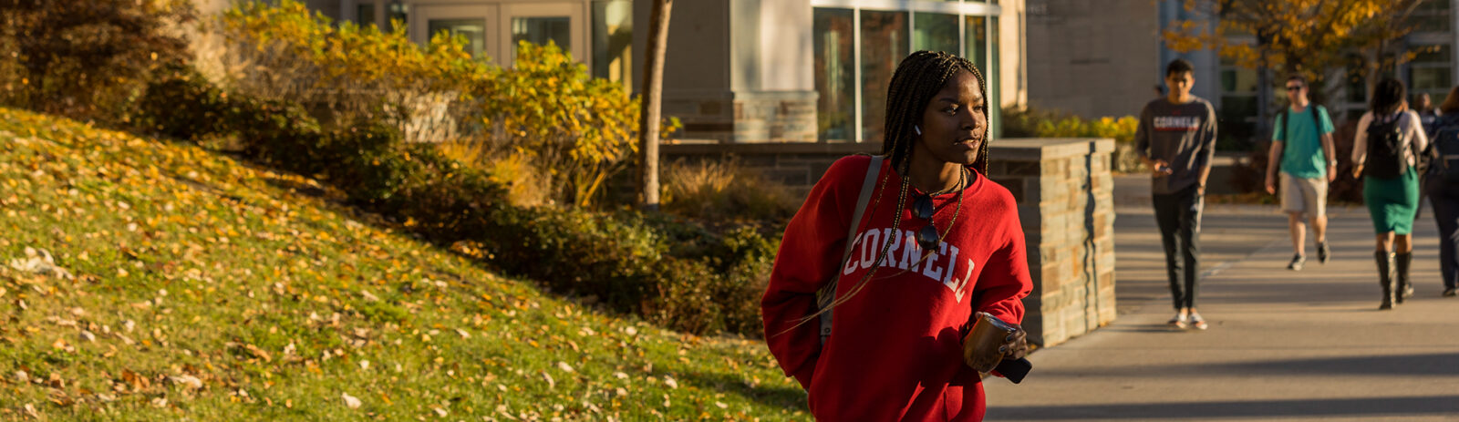 Student walking outside of Statler Hall on a sunny day.