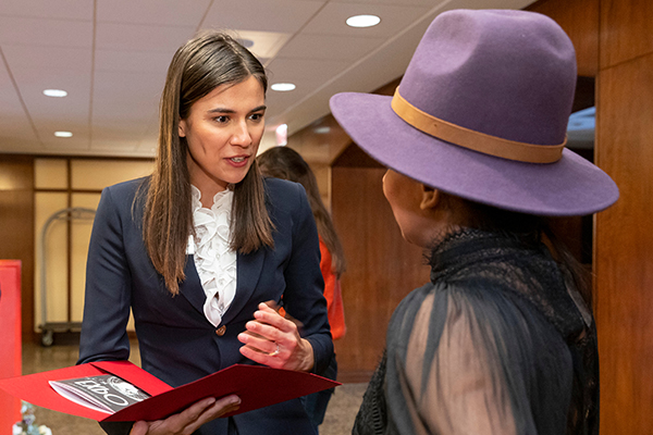 A person in business attire talking to a hotel guest.