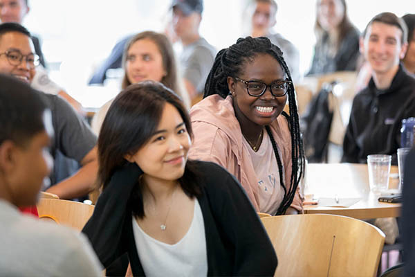 A person smiling while listening to someone talk.