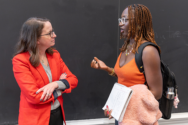 A student talking to an alumna in front of a chalkboard.