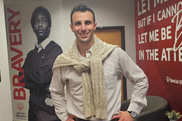Jason Woolf standing in the Special Olympics Pennsylvania (SOPA) office in front of banner walls