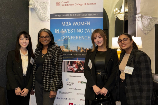Four women dressed in business professional attire in front of an “MBA Women in Investing Conference” banner. From networking to knowledge at the MBA Women in Investing Conference