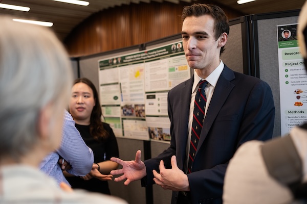 A student presents his project, CarbonWatch, to a symposium attendee.